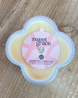 Sweet Grace candle in a clear container on a wooden surface