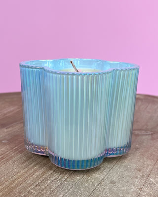 Hexagonal blue candle on a wooden surface with a pink background
