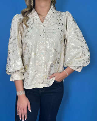 Ivory metallic blouse with abstract shimmer, ruffled V-neckline, button front, and puff sleeves.