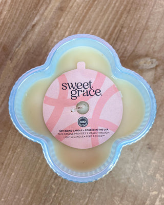 Sweet Grace candle in a floral container on a wooden surface