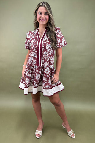 Woman wearing a maroon floral dress against a green background