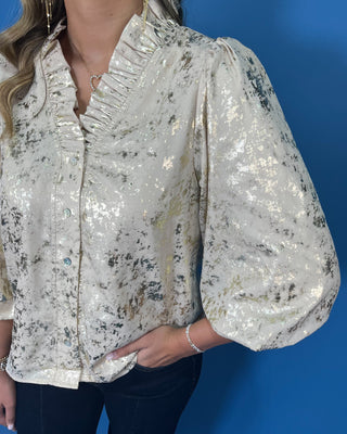 Ivory metallic blouse with abstract shimmer, ruffled V-neckline, button front, and puff sleeves.