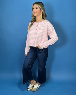 Pink and ivory striped knit cardigan with a round neckline, long sleeves, relaxed fit, and white button-front closure.