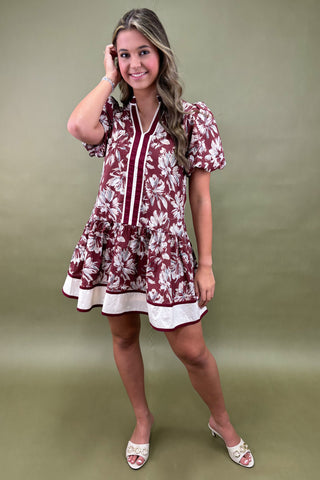 Woman wearing a maroon floral dress against a green background