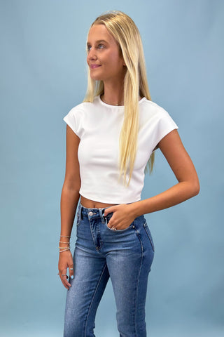 Woman wearing a white t-shirt and blue jeans against a light blue background