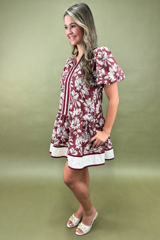 Woman wearing a maroon floral dress against a green background