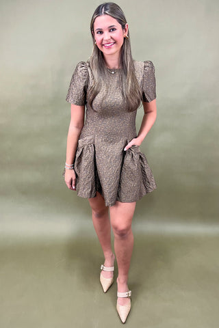 Woman wearing a patterned dress against a plain background