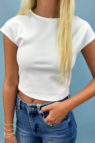 Person wearing a white crop top and blue jeans against a light blue background