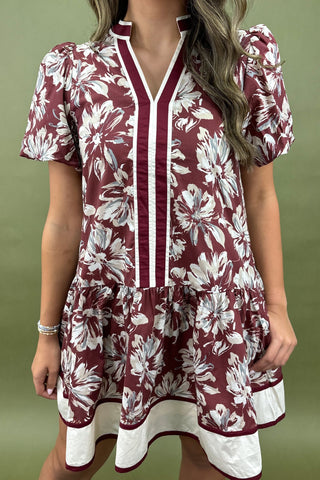 Woman wearing a maroon and white floral dress against a green background