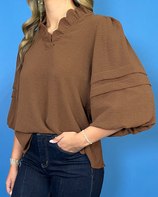 Chocolate brown blouse with a ruffled V-neckline, three-quarter balloon sleeves, and relaxed fit.