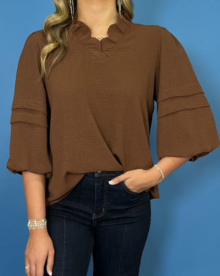 Chocolate brown blouse with a ruffled V-neckline, three-quarter balloon sleeves, and relaxed fit.