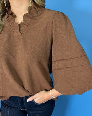 Chocolate brown blouse with a ruffled V-neckline, three-quarter balloon sleeves, and relaxed fit.