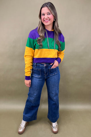 Woman wearing a colorful striped sweater and blue jeans against a beige background
