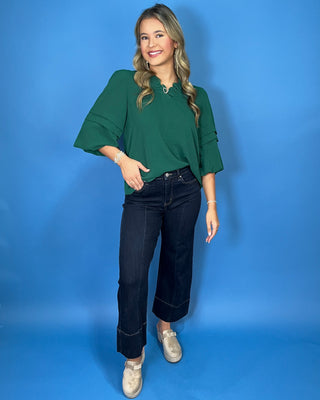Emerald green blouse with a ruffled V-neckline, three-quarter bell sleeves, and relaxed fit.