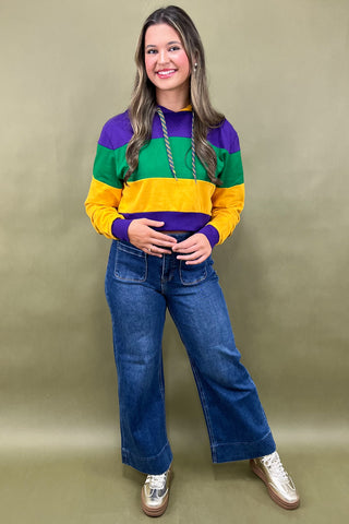 Woman wearing a colorful striped sweater and blue jeans on a beige background