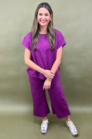Woman wearing a purple outfit against a green background