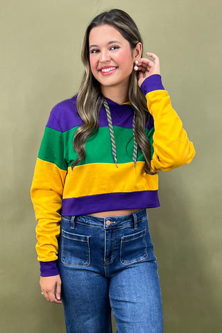 Woman wearing a colorful striped sweater and jeans against a plain background