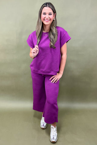 Woman wearing a purple outfit against a beige background