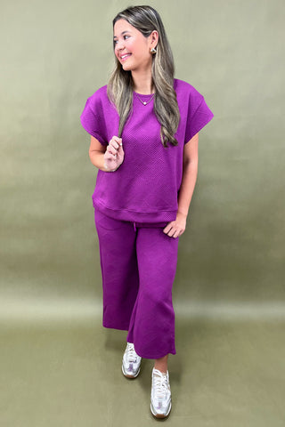 Woman wearing a purple outfit against a plain background
