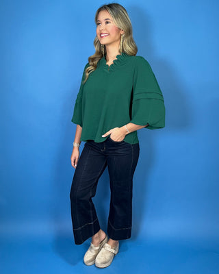 Emerald green blouse with a ruffled V-neckline, three-quarter bell sleeves, and relaxed fit.