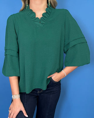 Emerald green blouse with a ruffled V-neckline, three-quarter bell sleeves, and relaxed fit.