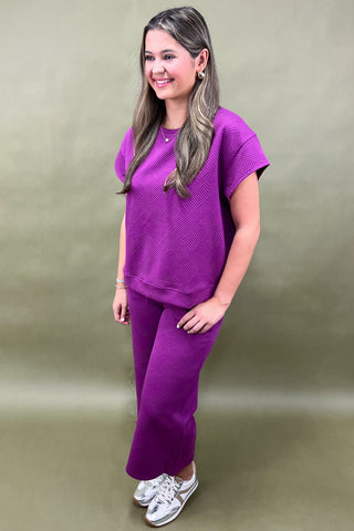 Woman wearing a purple outfit against a green background