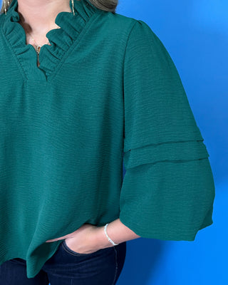 Emerald green blouse with a ruffled V-neckline, three-quarter bell sleeves, and relaxed fit.