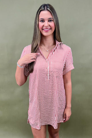 Red and white vertical striped button-down shirt dress with short sleeves and chest pocket, styled casually for a relaxed summer look