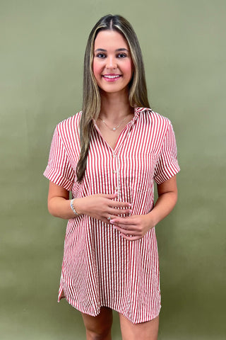 Red and white vertical striped button-down shirt dress with short sleeves and chest pocket, styled casually for a relaxed summer look
