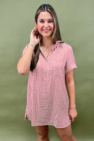 Red and white vertical striped button-down shirt dress with short sleeves and chest pocket, styled casually for a relaxed summer look