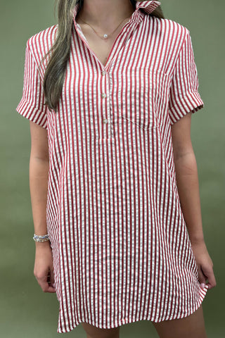 Red and white vertical striped button-down shirt dress with short sleeves and chest pocket, styled casually for a relaxed summer look