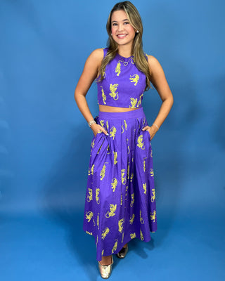 A woman modeling a purple two-piece set consisting of a sleeveless crop top and a long pleated skirt