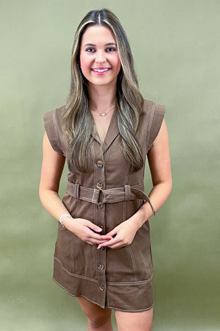 Woman wearing a brown sleeveless dress against a green background