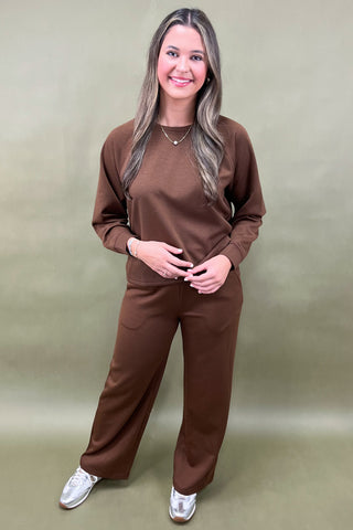 Woman wearing a brown outfit against a beige background