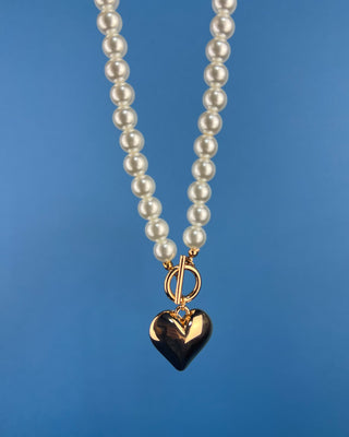 Shop the Heart Charm Pearl Necklace featuring classic faux pearls, a gold heart charm, and a stylish toggle clasp for timeless elegance.