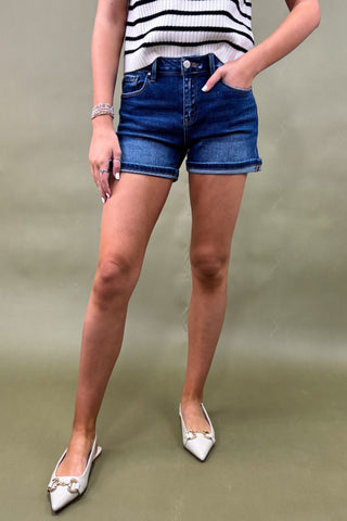 Person wearing blue denim shorts and a striped top on a plain background