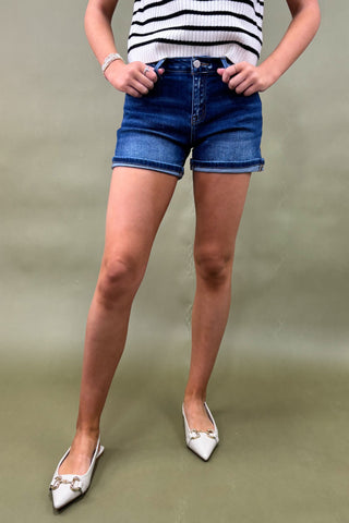 Person wearing a striped top and denim shorts on a plain background