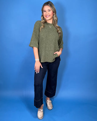 Olive green textured knit top with a round neckline, elbow-length sleeves, and relaxed fit.