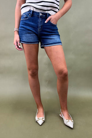 Person wearing blue denim shorts and a striped top on a plain background