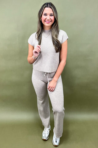 Woman wearing a gray outfit against a green background
