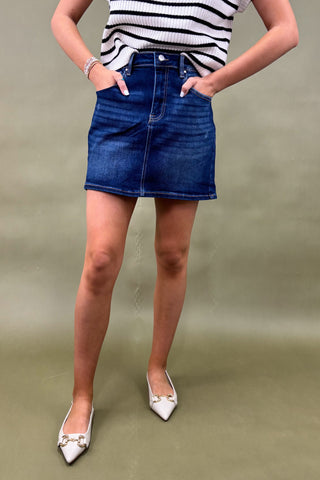Person wearing a blue denim skirt and striped top on a plain background