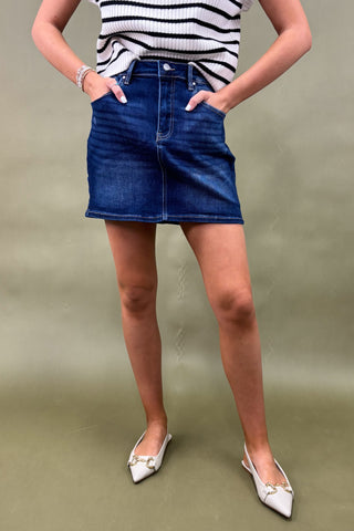 Person wearing a striped shirt and blue denim skirt on a plain background