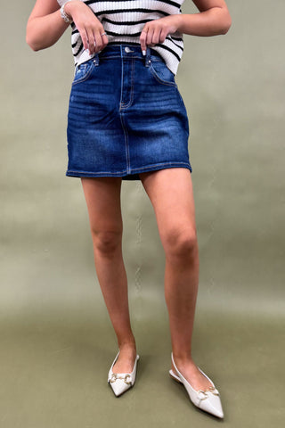 Person wearing a blue denim skirt and striped top on a plain background