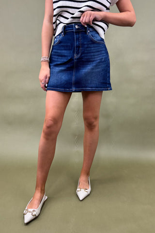 Person wearing a blue denim skirt and striped top on a plain background