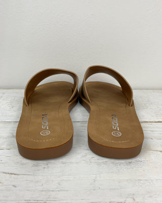 Pair of brown sandals on a light wooden surface