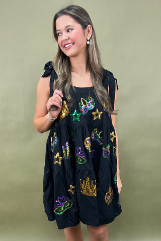 Woman wearing a black dress with colorful embroidery against a green background