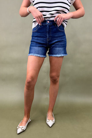 Person wearing blue denim shorts and a striped shirt on a plain background