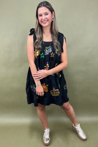 Woman wearing a black dress with colorful patterns on a green background