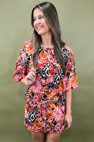 Woman wearing a colorful patterned dress against a green background