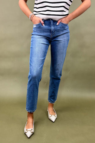 Person wearing blue jeans and a striped shirt on a green background